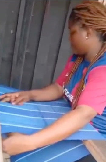 Person sitting on a bench wearing a blue and pink outfit with blurred face